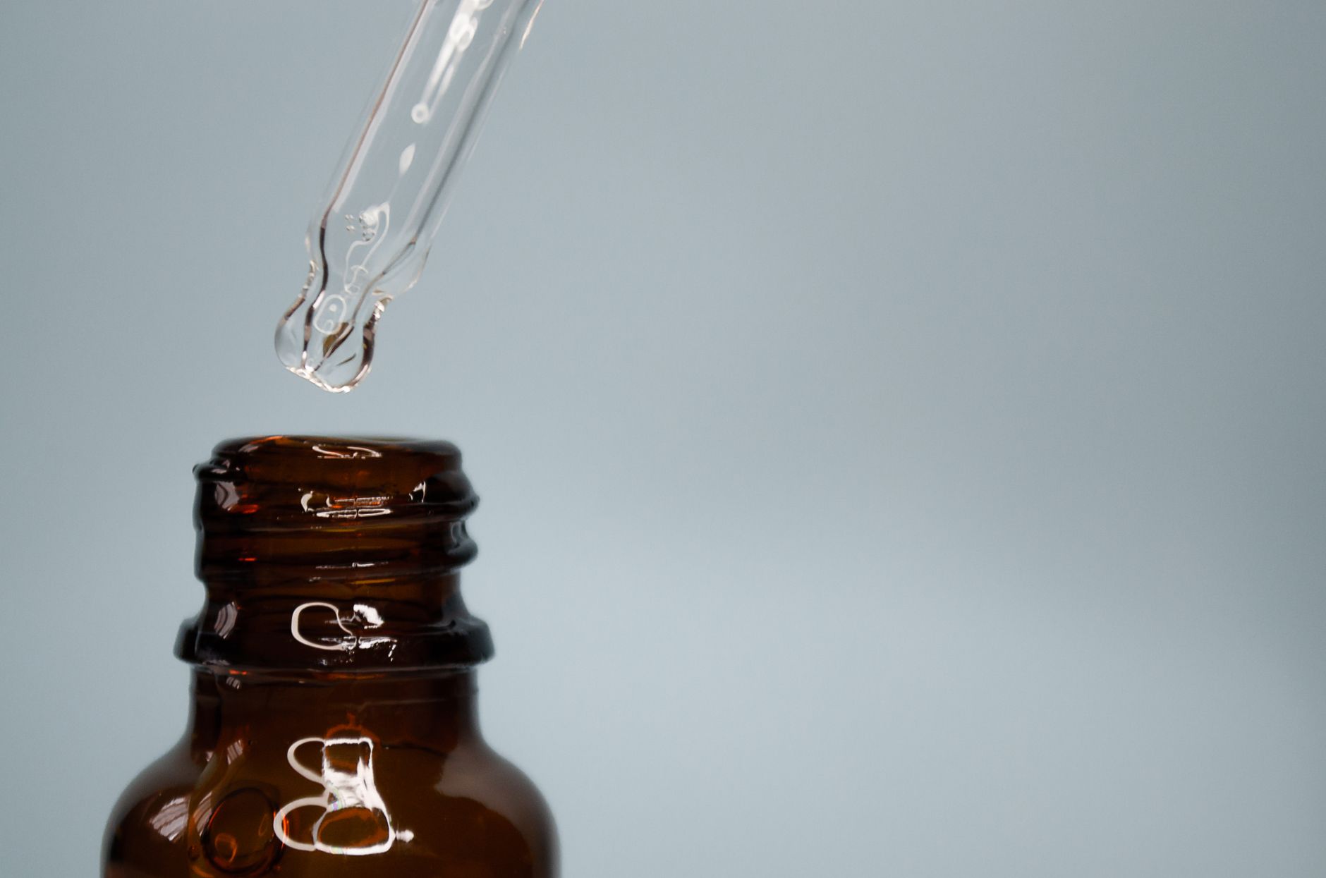 A minimal close-up of an amber glass bottle with a dropper