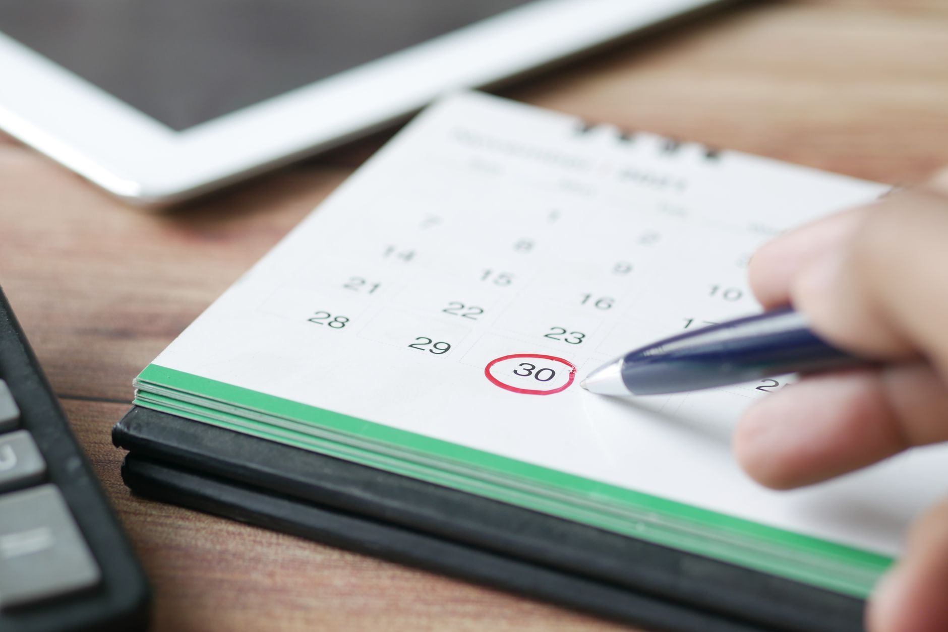 A person marking a date on a calendar, representing booking a confirmed schedule