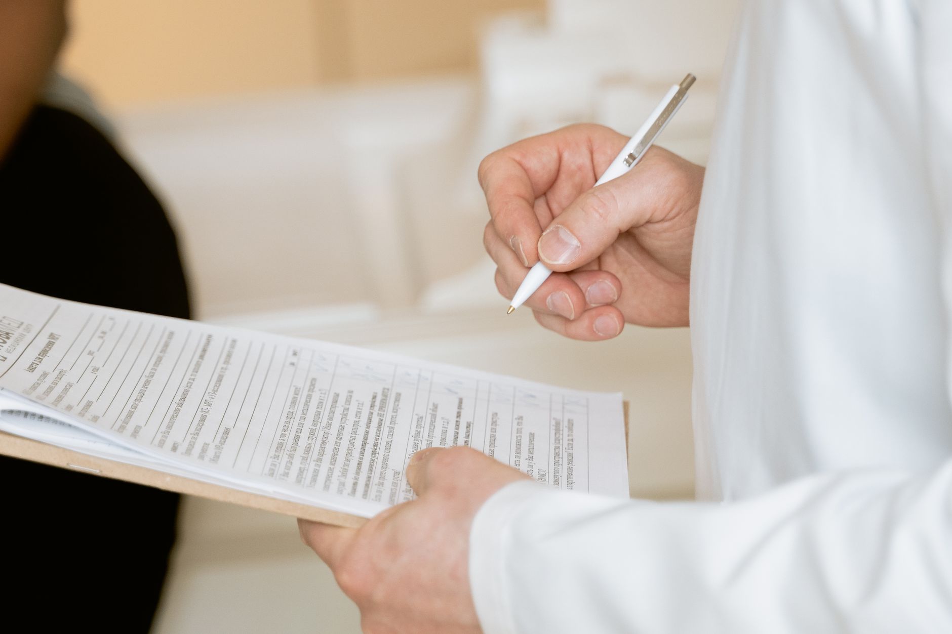 A clinician in a white coat reviewing a patient’s documentation on a clipboard