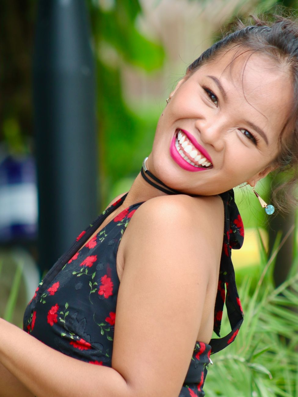 A smiling Filipina woman in a floral dress outdoors, confident and relaxed